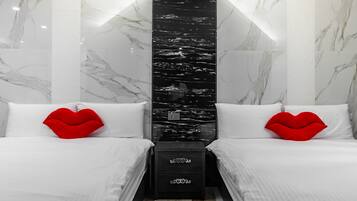 Una habitación de hotel moderna con dos camas, ropa de cama blanca y almohadas rojas en forma de corazón.