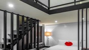 A modern hotel room with a staircase, a bed with a red pillow, a sofa, and a desk. - Sun Moon Tea Hotel (Yuchi)