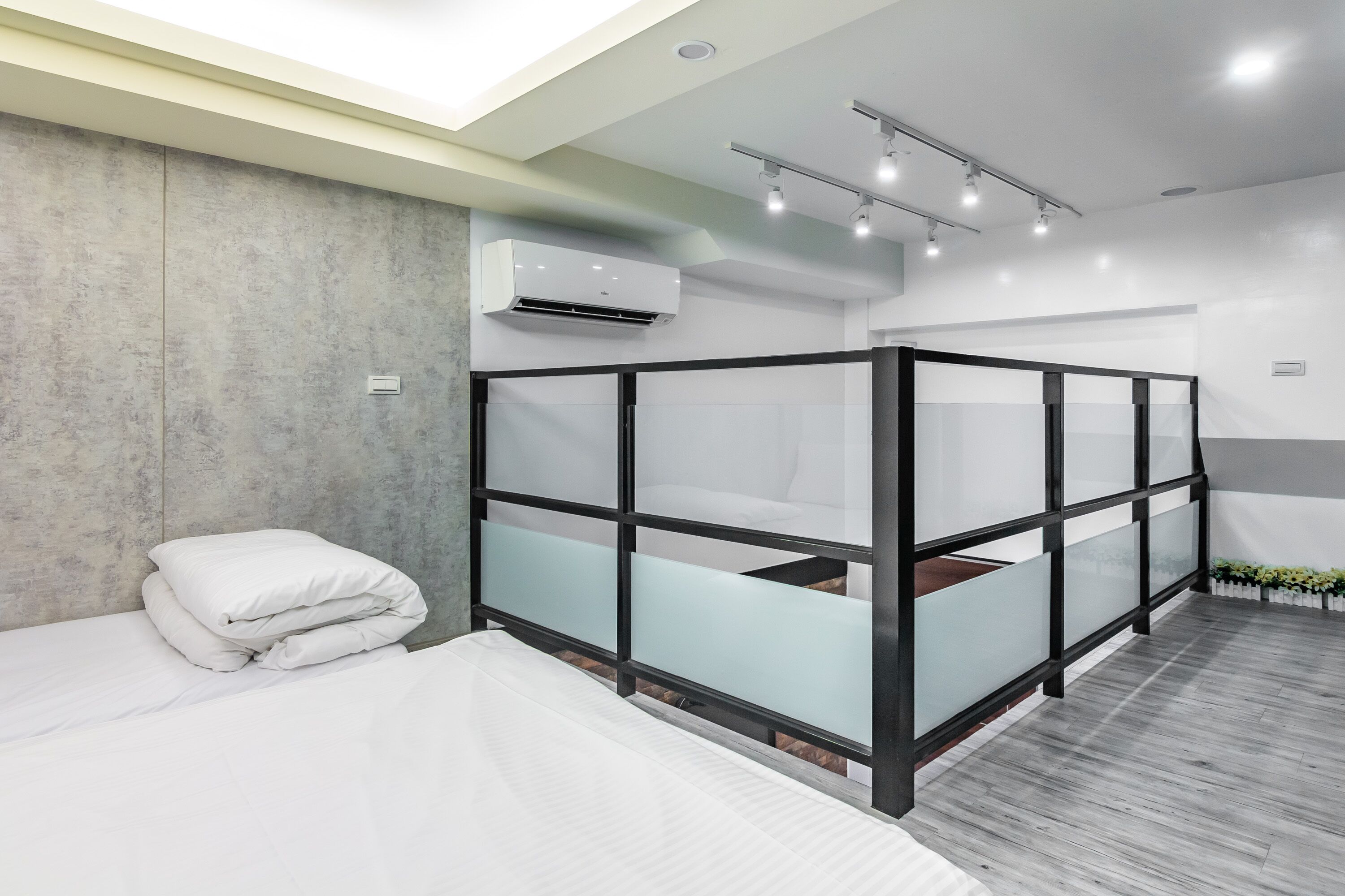 Een moderne hotelkamer met een bed, een glazen scheidingswand en een airconditioner.