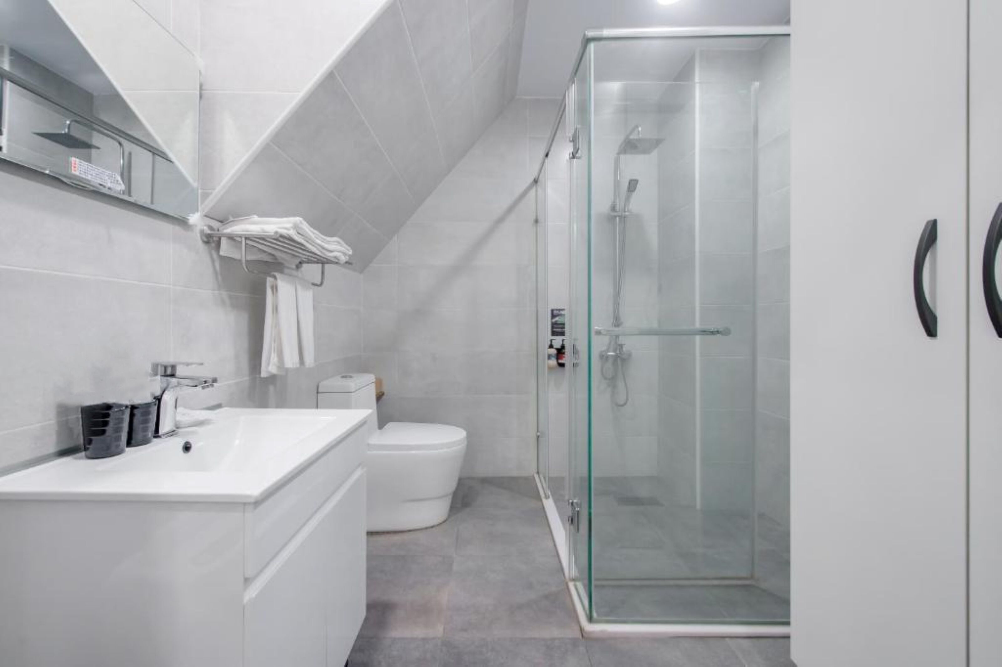 A modern bathroom with a glass-enclosed shower, a white sink, and a toilet.