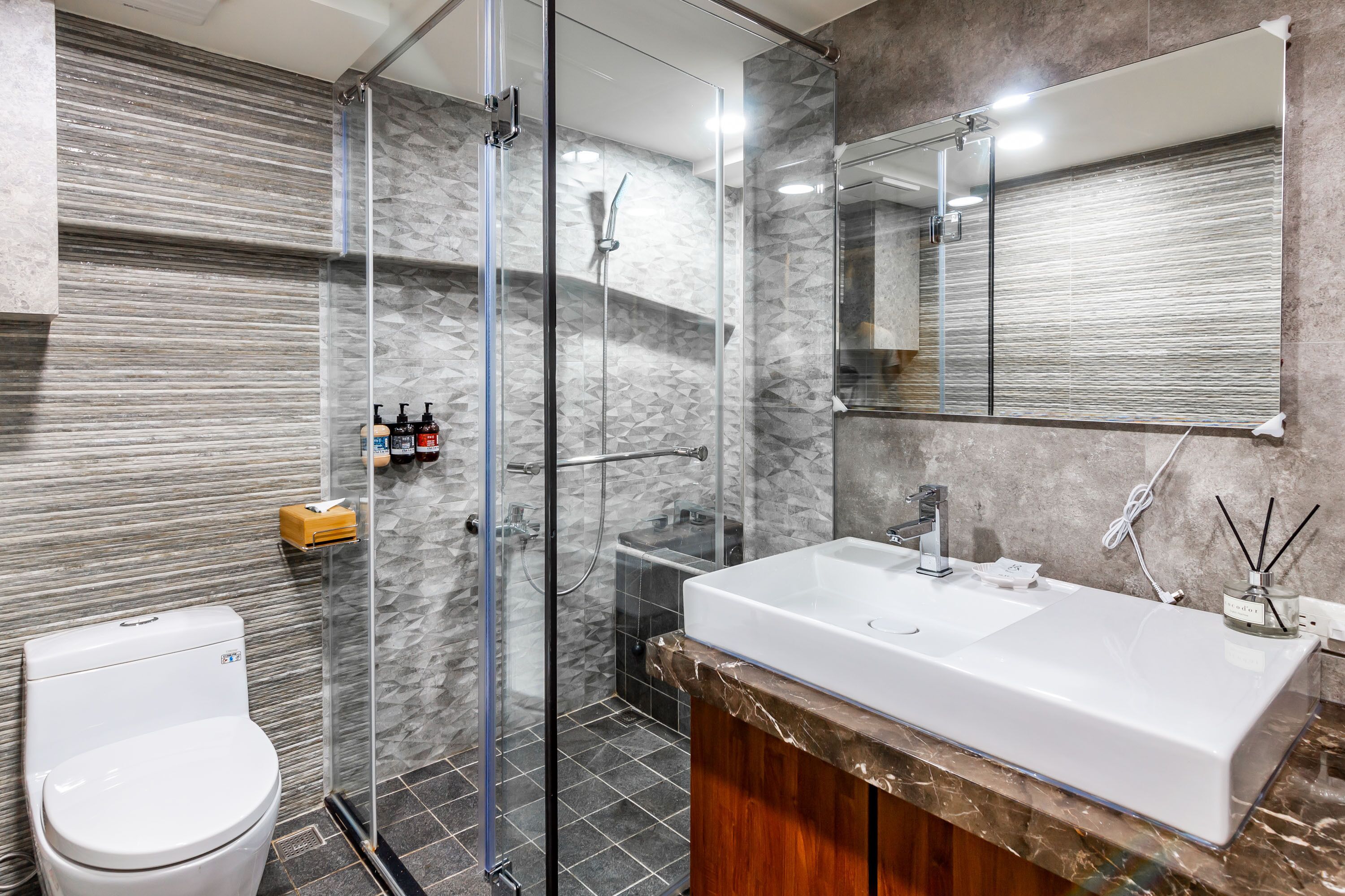 Une salle de bain moderne avec une douche à parois de verre, un lavabo blanc et un grand miroir.