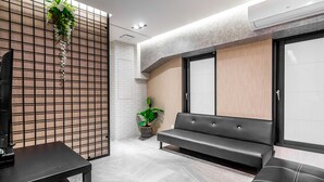 A modern waiting area with a sofa, a table, and a potted plant. - Sun Moon Tea Hotel (Yuchi)