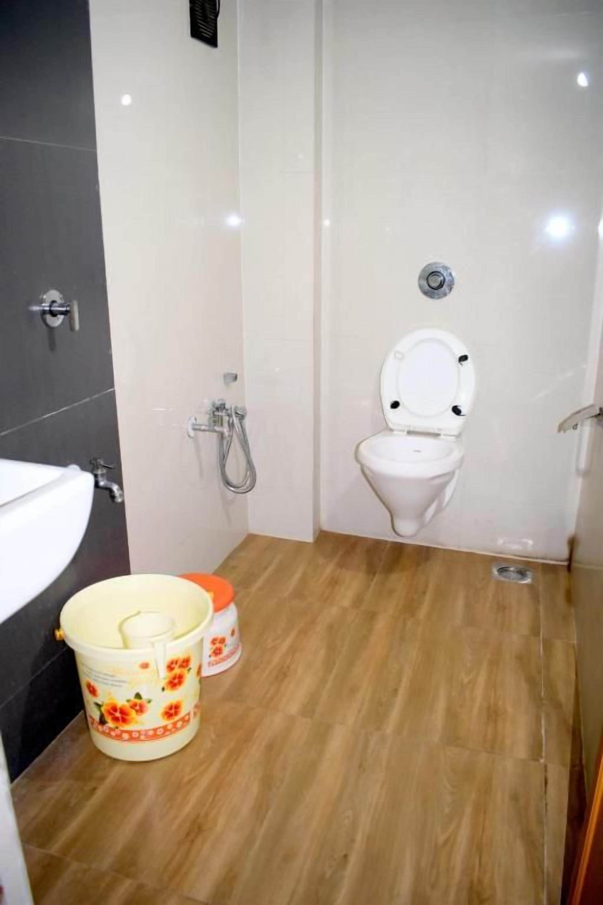 A bathroom with a toilet, a sink, and a shower. There are two buckets on the floor.