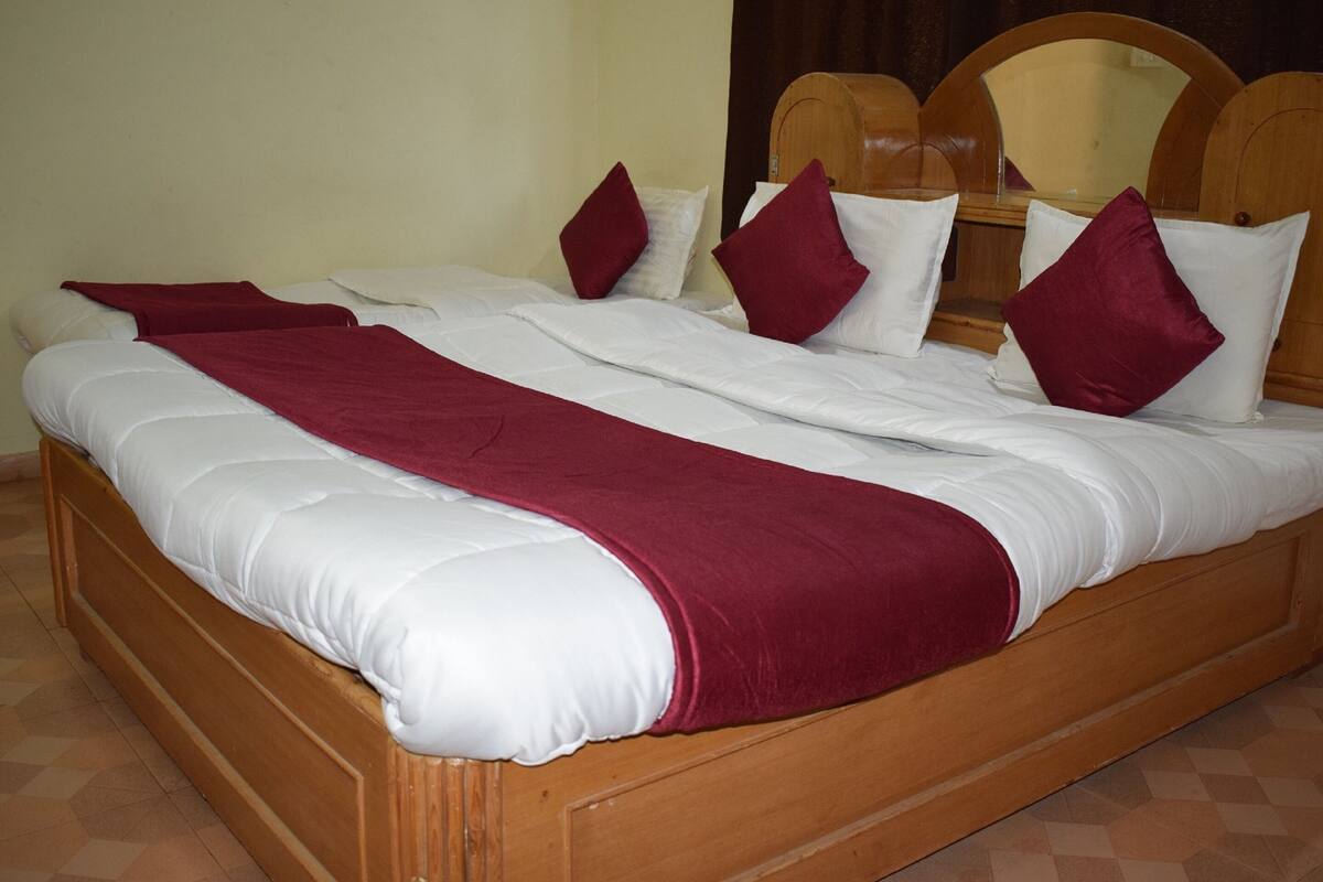 A large wooden bed with white and red bedding, a wooden headboard, and a tiled floor.
