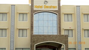 Un hotel chiamato "Hotel Darshan", caratterizzato da un ingresso ad arco ben evidente e una facciata in tegole.