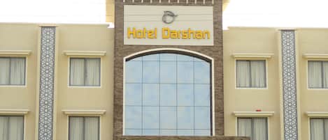 Un hotel llamado "Hotel Darshan" con una entrada abovedada destacada y fachada de tejas.