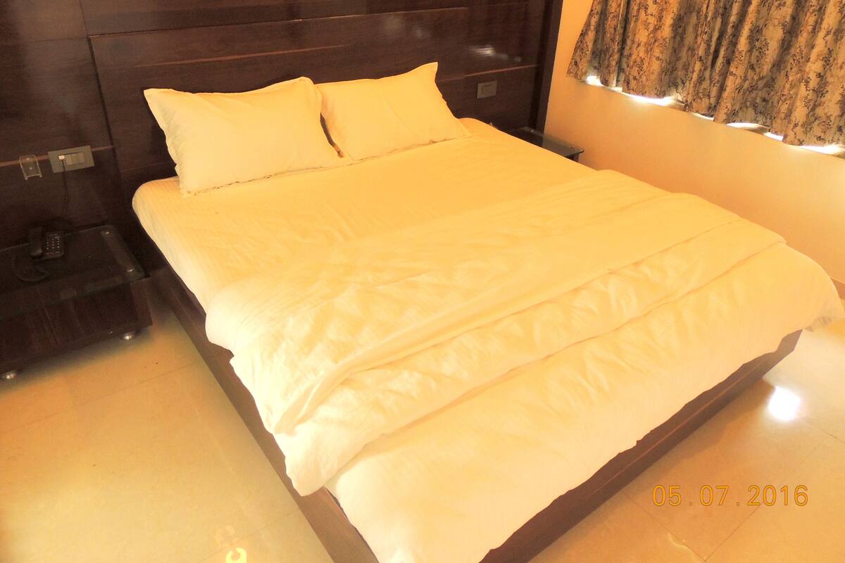 Cama bem arrumada com lençóis brancos em um quarto de hotel.