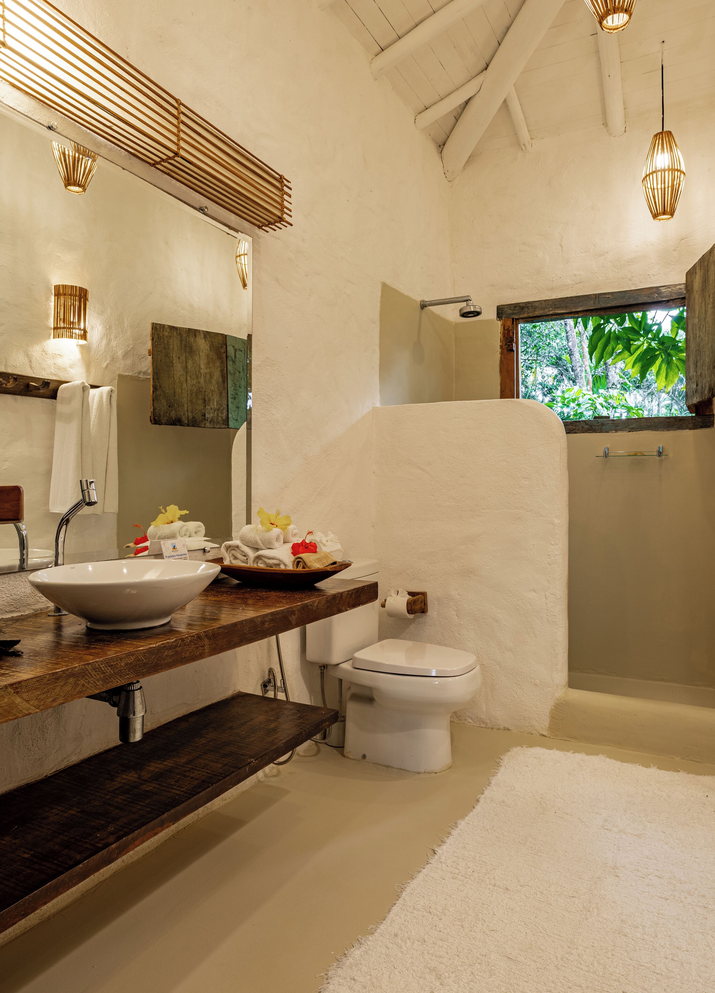 Un baño con un lavamanos grande y blanco, un inodoro y una bañera. Hay una ventana con vistas a zonas verdes.