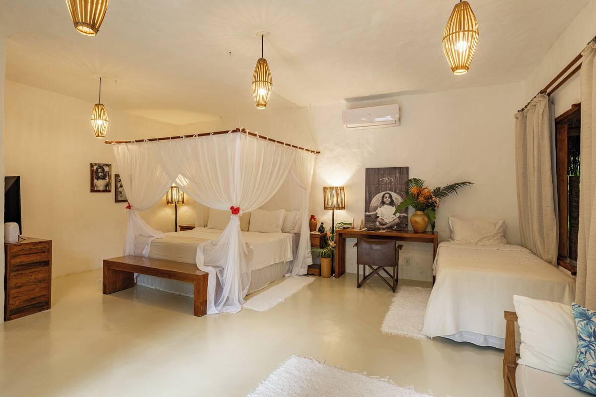 Un espacioso dormitorio con cama con dosel, dos mesitas de noche, un escritorio y una silla.
