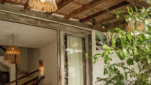 A rustic interior with a wooden ceiling, a woven light fixture, a wooden bench, and various potted plants. - Hotel Boutique Bahia Bonita (Porto Seguro)