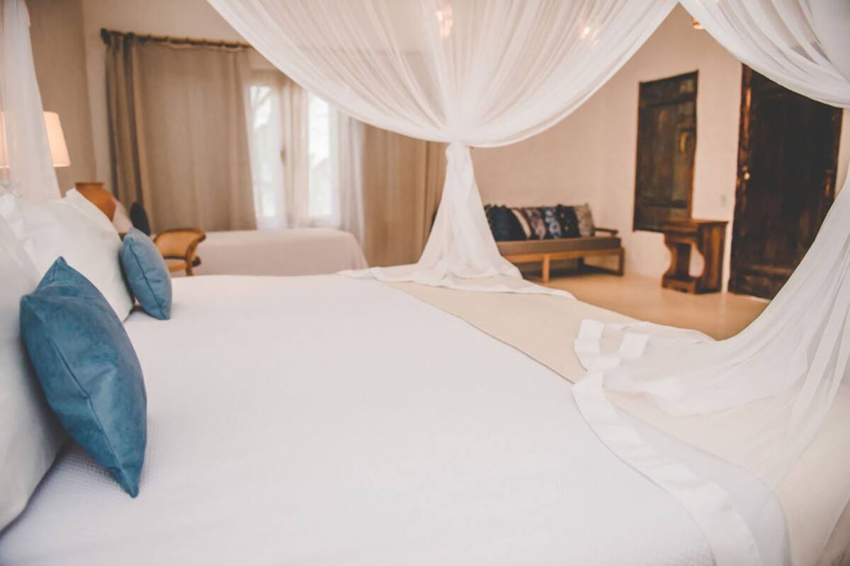 Un dormitorio con una cama grande, dosel y vista a una habitación con un cuadro.