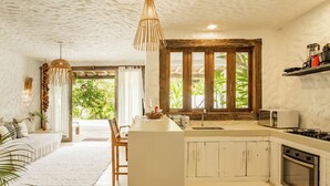 A spacious kitchen with a large island, wooden cabinets, and a view of greenery outside. - Hotel Boutique Bahia Bonita (Porto Seguro)