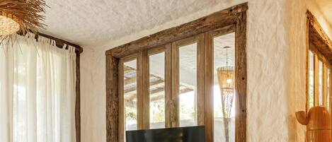 A cozy living room with a wooden bench, a TV on a wooden stand, and a rustic window.