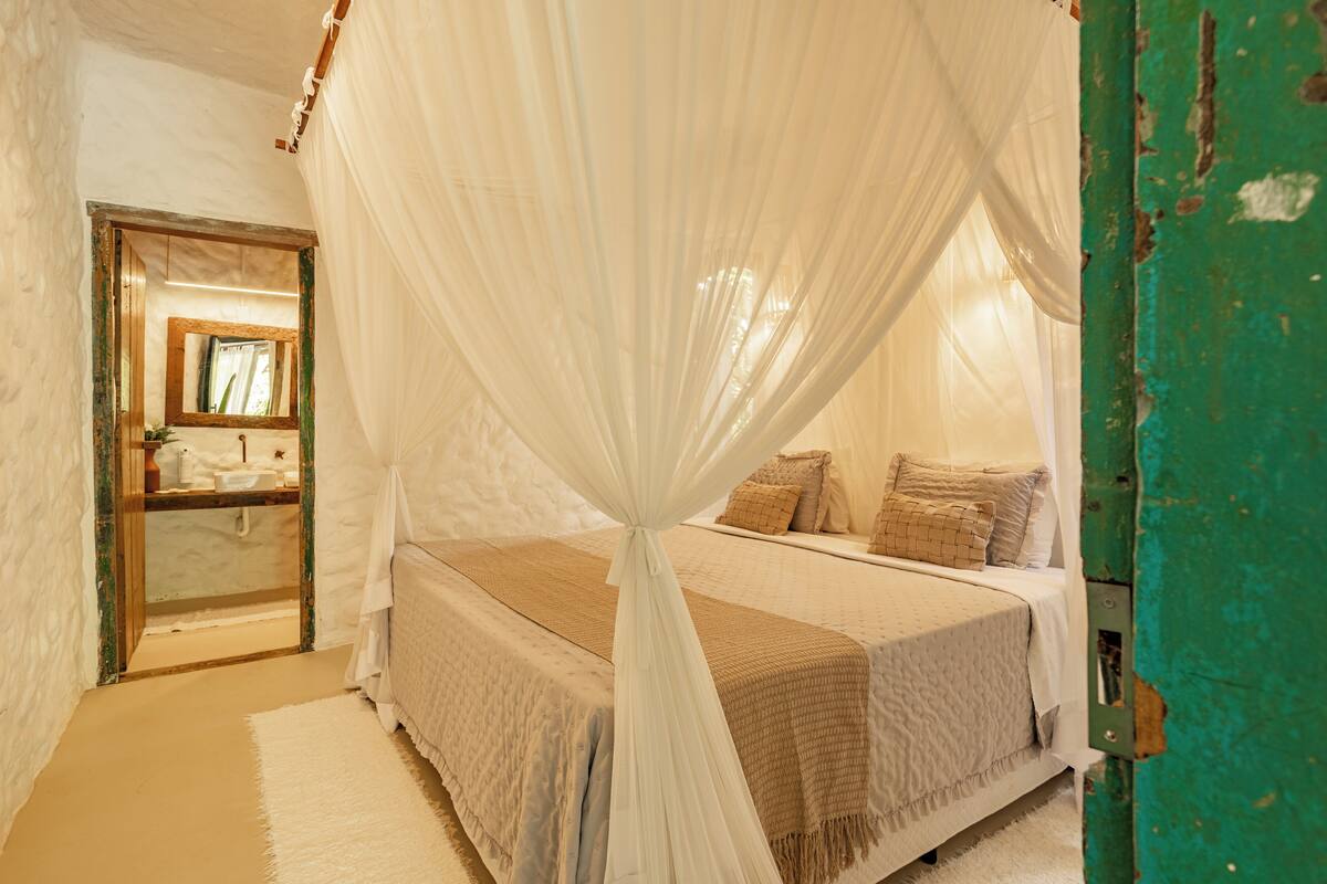 Un dormitorio con cama con dosel, un espejo y una puerta verde.