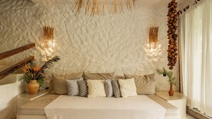 A bedroom with a textured ceiling, a bed with multiple pillows, a bedside table with a vase, and a hanging decoration. - Hotel Boutique Bahia Bonita (Porto Seguro)