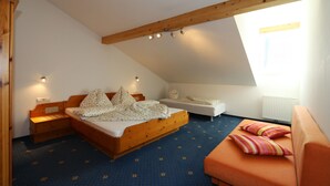 Une chambre avec un lit en bois, un petit canapé et une fenêtre laissant entrer la lumière naturelle.