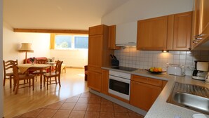 Une cuisine dotée de meubles en bois, d’une cuisinière, d’un évier et d’un coin repas avec une table et des chaises.