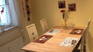 A dining area with a wooden table, white chairs, and a wall decorated with coffee-themed decals and pictures.