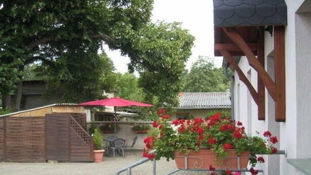 A patio area with potted plants and a red umbrella.