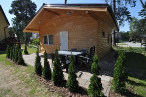 Una cabaña de madera con un porche, una mesa y sillas.