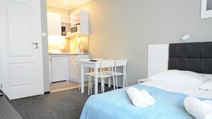 Et hotelværelse med en seng, et skrivebord og en stol. Der er en mikrobølgeovn og en kaffemaskine på bordet.