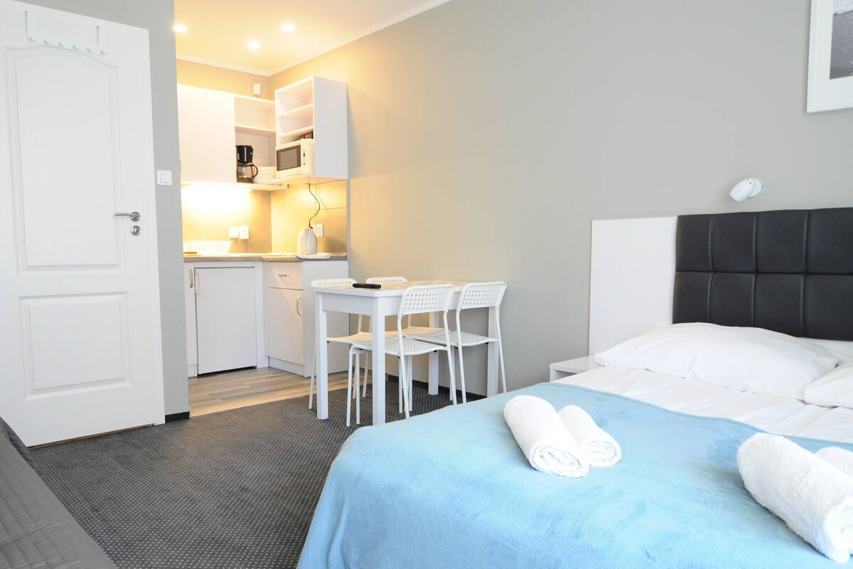 Ein Hotelzimmer mit einem Bett, einem Schreibtisch und einem Sessel. Auf der Ablage befinden sich eine Mikrowelle und eine Kaffeemaschine.