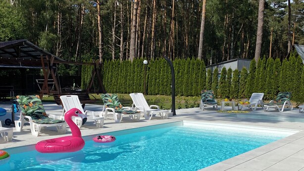 En swimmingpool med liggestole og en lyserød flamingo-svømmebøje.