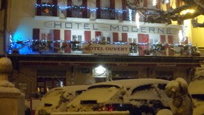 Un hôtel avec une enseigne indiquant « HÔTEL MODERNE » et « HÔTEL OUVERT ».