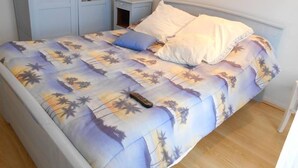 Un lit avec une couvre-lit à motifs floraux, une table de chevet, une commode et une armoire.