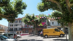 Un fourgon jaune est garé dans une rue bordée d’arbres et de bâtiments.