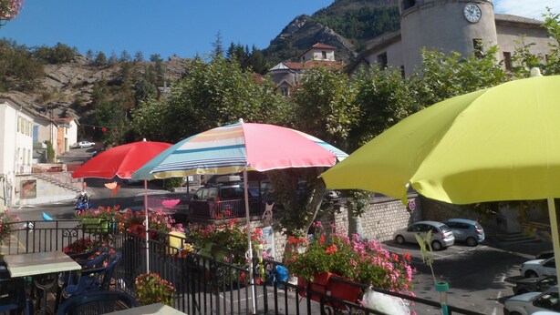 Une rue bordée de parasols colorés, une tour de l’horloge et des bâtiments dotés de balcons.