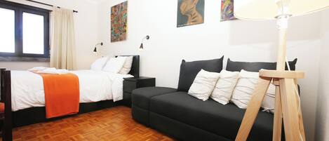 Una habitación con cama, sofá, lámpara y obras de arte en las paredes.