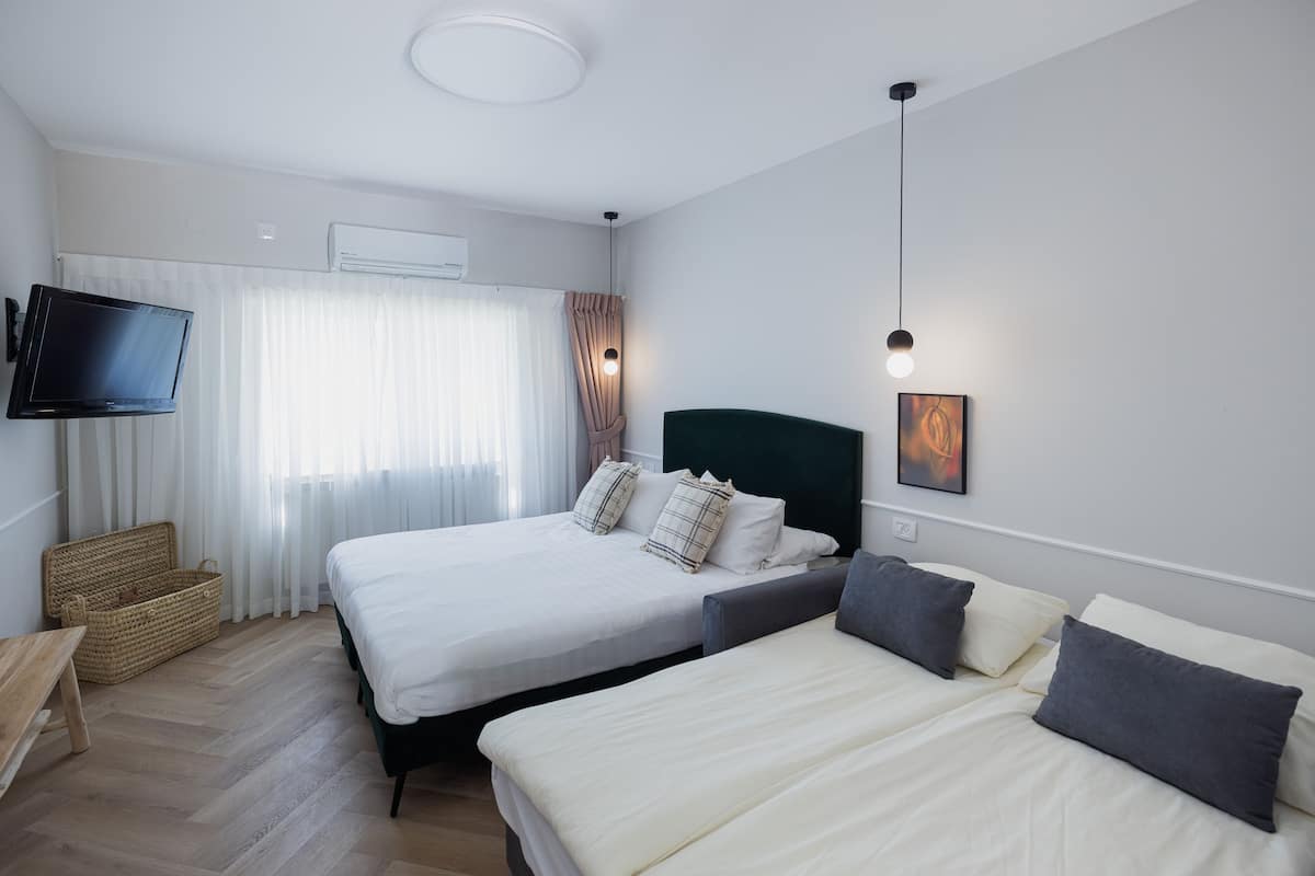 Een hotelkamer met twee bedden, een flatscreen televisie aan de muur, een houten bankje en een geweven mand.