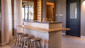 Een keuken met een houten eiland, barstoelen en een donkere deur.