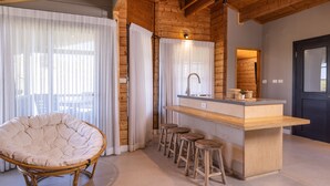 Een moderne keuken met een houten keukeneiland, barkrukken en een hangstoel.