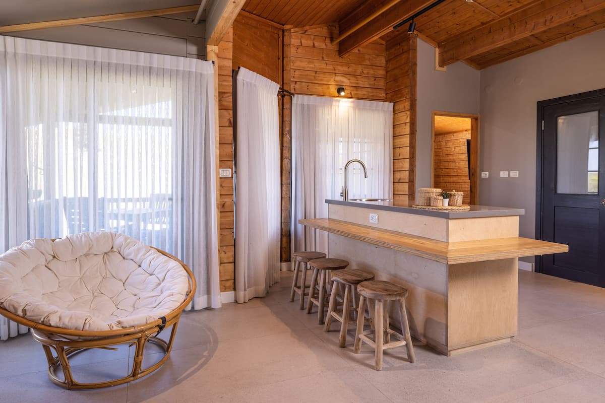 Een moderne keuken met een houten keukeneiland, barkrukken en een hangstoel.