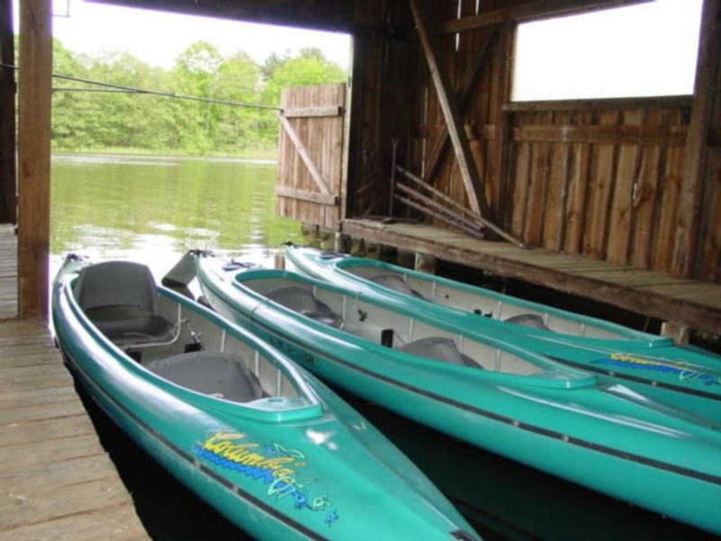 A covered dock with three kayaks lined up.
