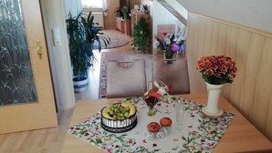 A room with a wooden table set with fruits, a vase of flowers, and a small decorative item. - Apartment in Starsow (21456) (Mirow)