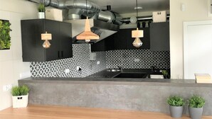 A modern kitchen with a wooden countertop, black cabinets, and pendant lights. - Pelikan Resort (Kolobrzeg)