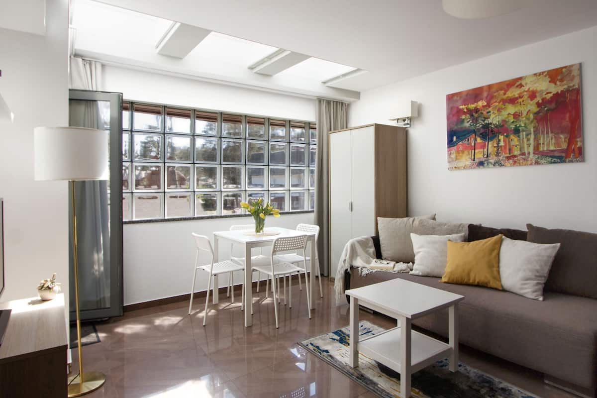 Ein modernes Wohnzimmer mit Sofa, Couchtisch und einem Essbereich mit Stühlen und Tisch.