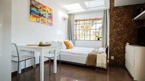 A room with a bed, a desk, and a chair. There is a window with curtains, a painting on the wall, and a television on a stand. - Pelikan Resort (Kolobrzeg)