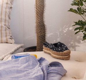 Ein gemütliches Zimmer mit einem Bett, einem Kaktus und einem Schuhpaar auf dem Bett.