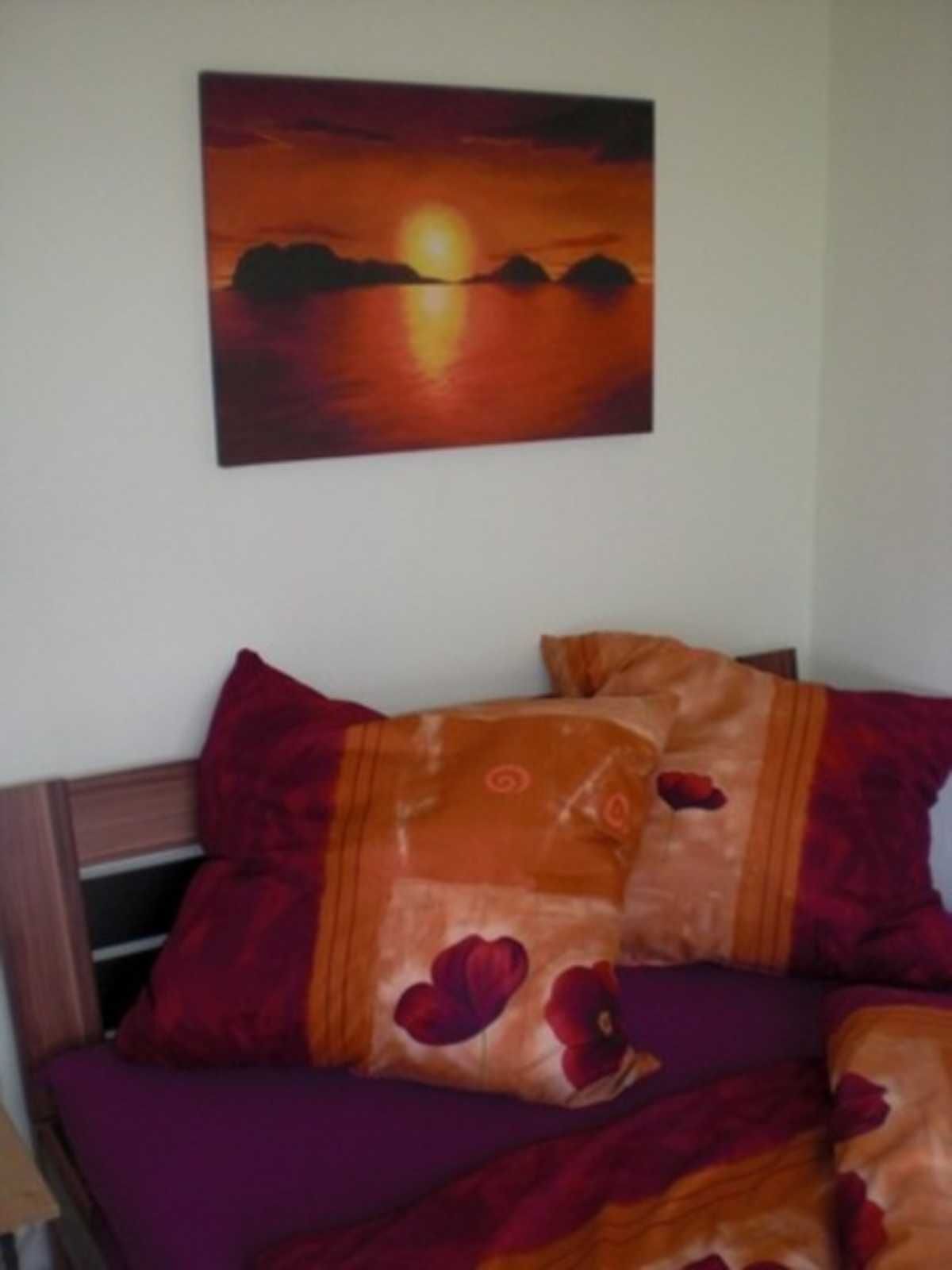 A bed with a purple bedspread and two pillows with a floral pattern.