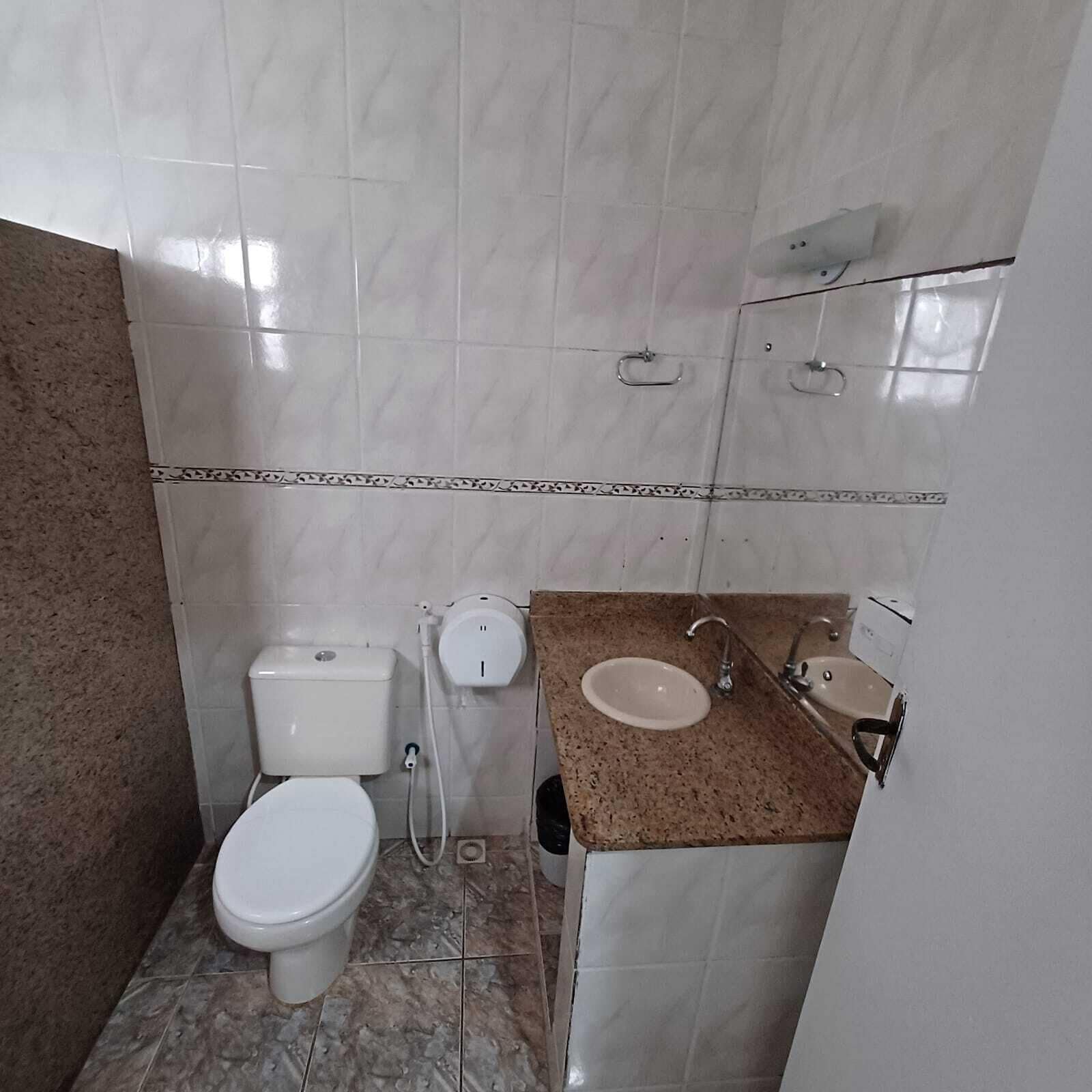 A small bathroom with a toilet, sink, and shower.