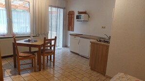 A compact kitchen with a dining table, chairs, a microwave, and a small cabinet.