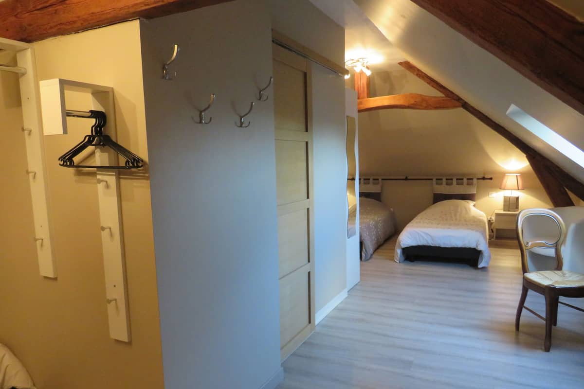 Et soveværelse med træloft, seng, stol og et natbord med lampe.