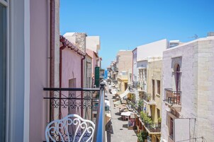 Ένας στενός δρόμος με κτίρια και στις δύο πλευρές, μπαλκόνια με κάγκελα και υπαίθριοι χώροι για καθιστικό.