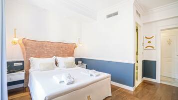 A neatly made bed with white linens and towels, a wooden nightstand with a lamp, and a blue accent wall.