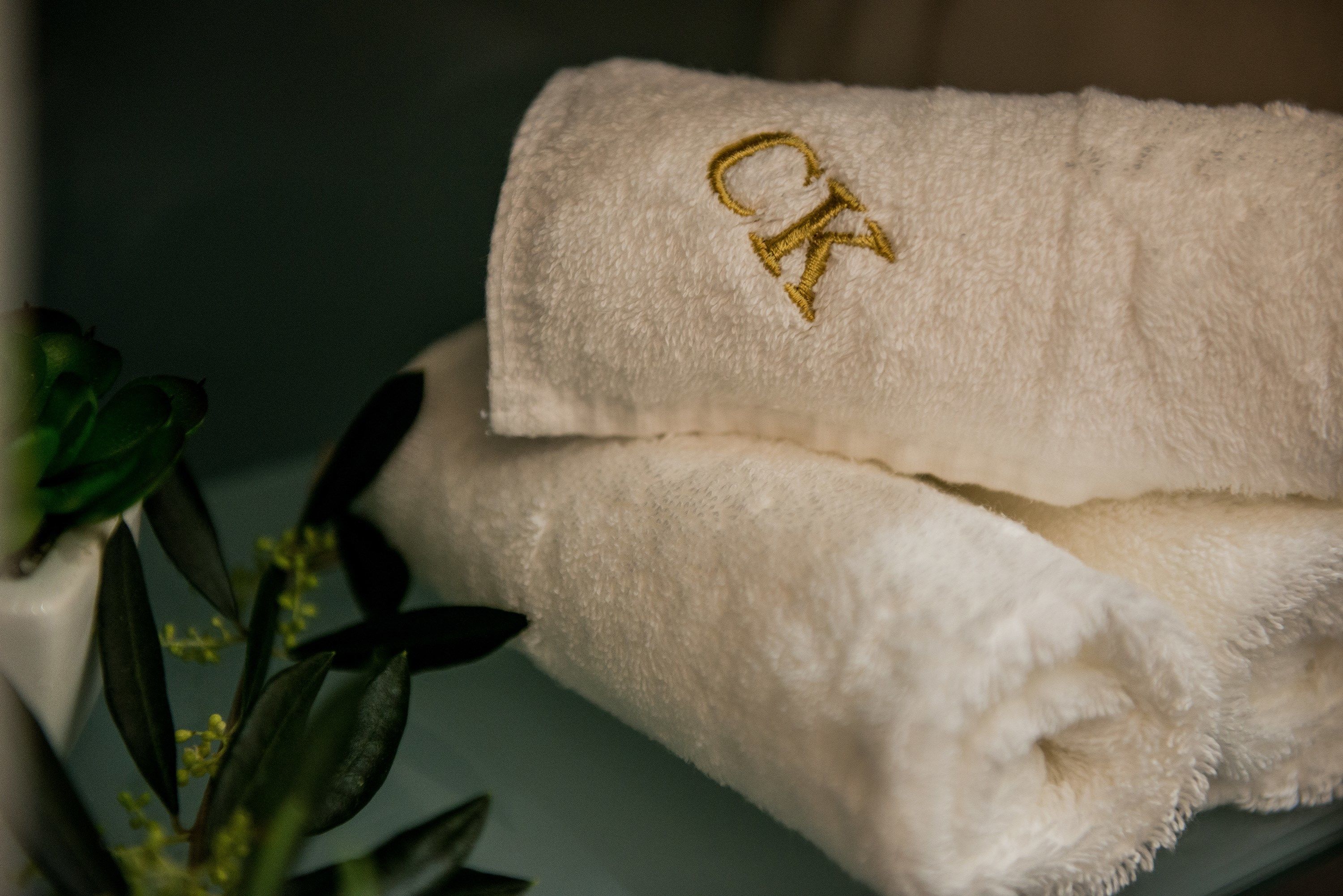 A folded white towel with a gold embroidered letter 'K'.