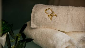 A folded white towel with a gold embroidered letter 'K'.